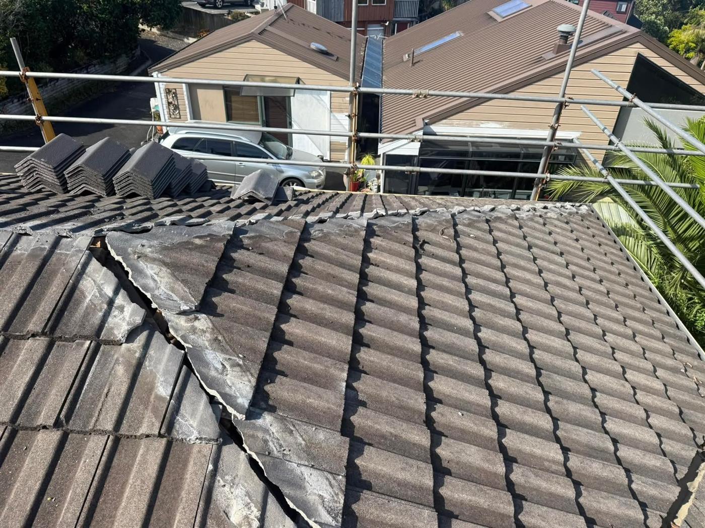 Tiles lifted along a roof valley with scaffolding up and stacked tiles beside the working area