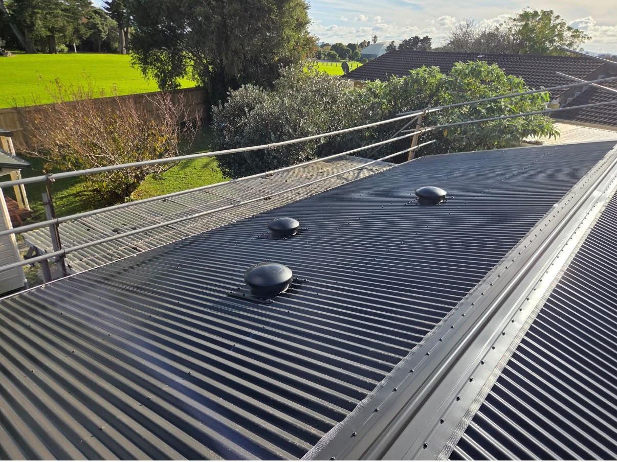 A finished dark long-run roof on an Auckland home, edge protection rails still in place