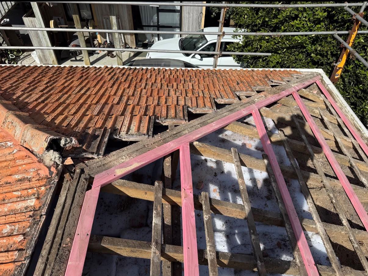 An old concrete tile roof part-stripped, with the original tiles still on one hip